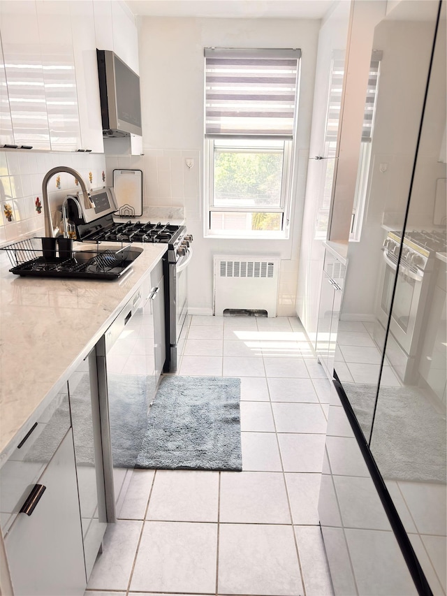 30-11 Parsons Blvd Unit 3P, Flushing, NY 11354 - kitchen with radiator, stainless steel range with gas stovetop, dishwashing machine, white cabinetry, and light tile patterned floors