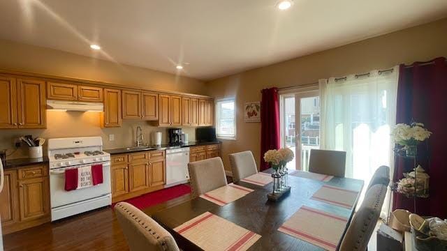 2568 Seminole Ave, Seaford, NY 11783 - kitchen with white appliances, under cabinet range hood, dark countertops, dark wood-type flooring, and recessed lighting