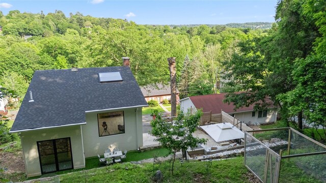 290 Mountain Rd, Pleasantville, NY 10570 - back of house featuring roof with shingles, a forest view, stucco siding, and a chimney