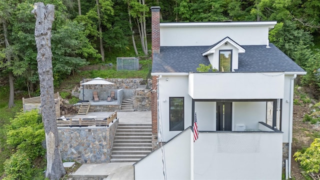 290 Mountain Rd, Pleasantville, NY 10570 - contemporary house featuring stairs, stucco siding, a chimney, a shingled roof, and a patio