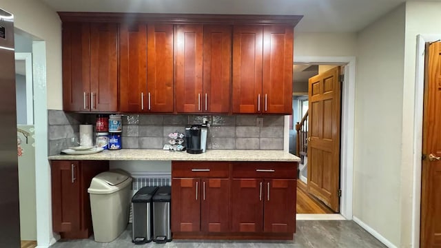 136-23 61st Rd, Flushing, NY 11367 - kitchen featuring decorative backsplash, baseboards, light stone countertops, and reddish brown cabinets