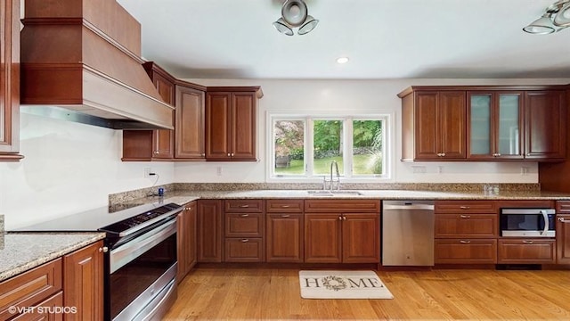 1002 Kitchawan Rd, Ossining, NY 10562 - kitchen with stainless steel appliances, premium range hood, light wood finished floors, glass insert cabinets, and light stone countertops