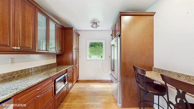 1002 Kitchawan Rd, Ossining, NY 10562 - kitchen with stainless steel appliances, light wood-type flooring, light stone countertops, and glass insert cabinets