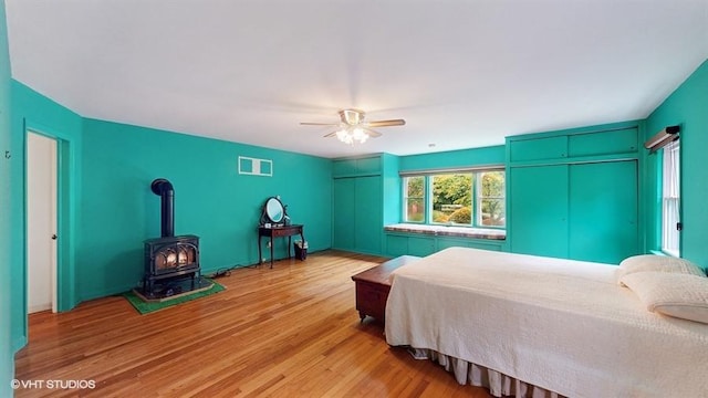 1002 Kitchawan Rd, Ossining, NY 10562 - bedroom with light wood finished floors, a wood stove, and ceiling fan