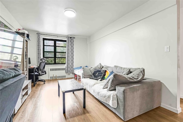 26-20 141st St Unit 4A, Flushing, NY 11354 - living area with radiator heating unit, a desk, wood finished floors, and baseboards