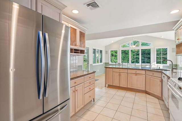 109 Dogwood Ln, Port Jefferson, NY 11777 - kitchen with white appliances, vaulted ceiling, stone counters, a peninsula, and light brown cabinets
