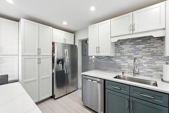 26 Fieldmere St, Elmont, NY 11003 - kitchen with appliances with stainless steel finishes, light countertops, light wood finished floors, white cabinets, and decorative backsplash