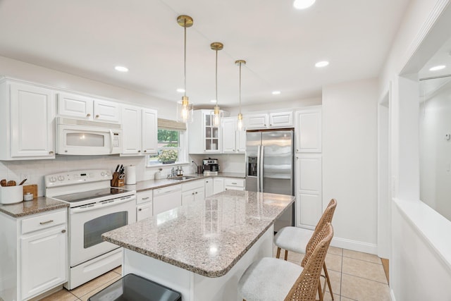 52 Iroquois Trl, Ridge, NY 11961 - kitchen featuring white appliances, a kitchen breakfast bar, a sink, light tile patterned flooring, and white cabinetry