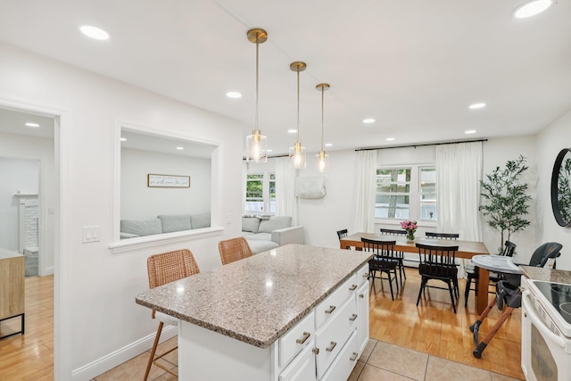 52 Iroquois Trl, Ridge, NY 11961 - kitchen featuring white cabinets, electric range, a center island, a kitchen bar, and light stone counters