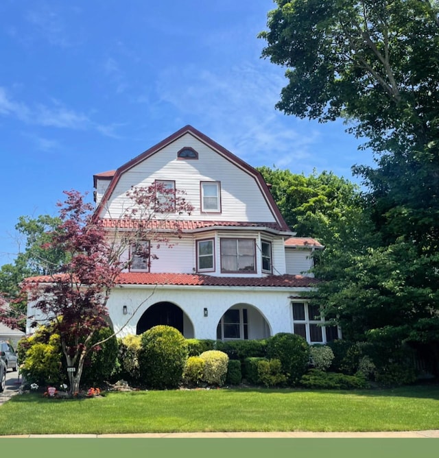 240 Oakwood Ave, Cedarhurst, NY 11516 - colonial inspired home featuring a gambrel roof, a front yard, and stucco siding
