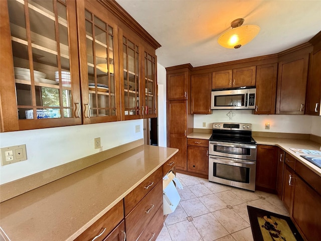 17 Wilson Rd, Brewster, NY 10509 - kitchen featuring stainless steel appliances, light countertops, glass insert cabinets, light tile patterned flooring, and brown cabinetry