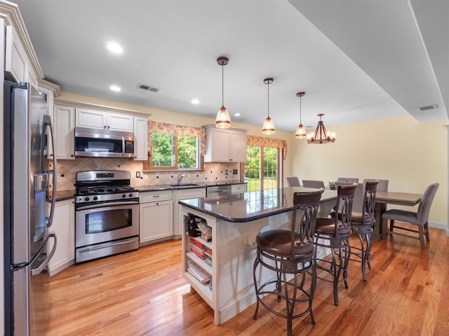 15 Tennyson Dr, Nanuet, NY 10954 - kitchen featuring appliances with stainless steel finishes, a sink, a breakfast bar area, light wood-style flooring, and tasteful backsplash