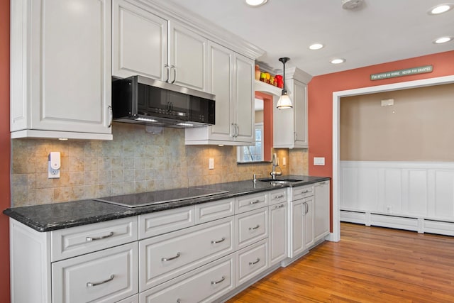 81 Brunswick Rd, Ronkonkoma, NY 11779 - kitchen featuring a sink, black electric cooktop, stainless steel microwave, white cabinets, and light wood-type flooring