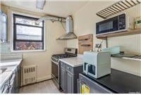 63-95 Austin St Unit 2F, Rego Park, NY 11374 - kitchen featuring stainless steel range with gas cooktop, black microwave, range hood, and light countertops