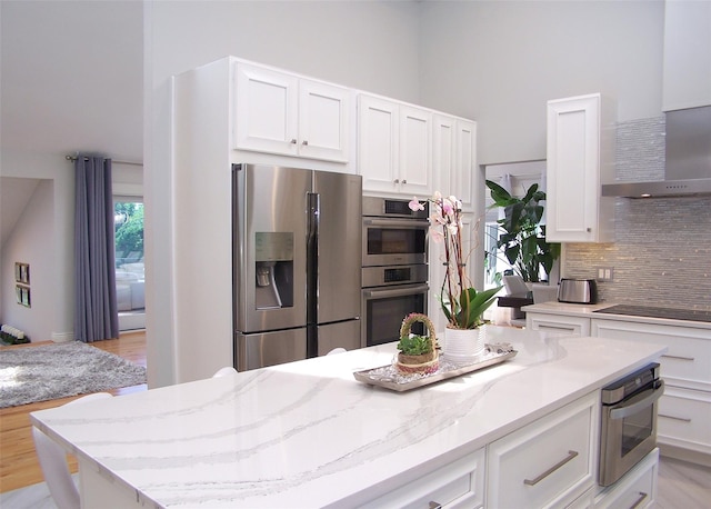 12 Sound View Dr, Rocky Point, NY 11778 - kitchen with stainless steel appliances, wall chimney range hood, a high ceiling, tasteful backsplash, and light stone countertops