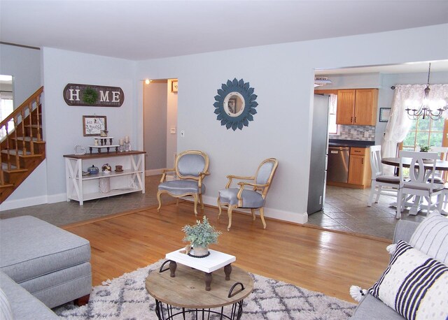 53 Admiral St, Port Jefferson Station, NY 11776 - living room featuring stairway, a chandelier, light wood-style floors, and baseboards