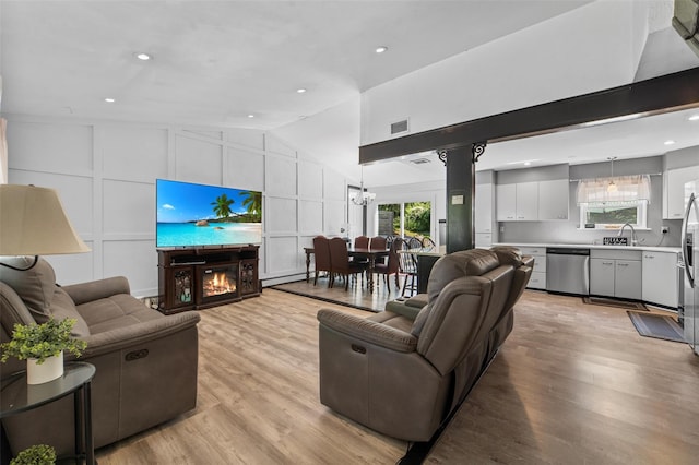 59 Oslo Dr, Yorktown Heights, NY 10598 - living room featuring a decorative wall, a warm lit fireplace, lofted ceiling, light wood-style floors, and a chandelier