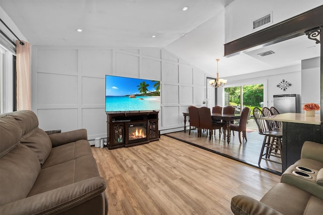 59 Oslo Dr, Yorktown Heights, NY 10598 - living room with a decorative wall, a chandelier, baseboard heating, vaulted ceiling, and a glass covered fireplace