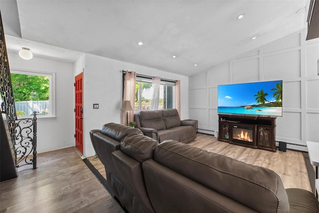 59 Oslo Dr, Yorktown Heights, NY 10598 - living room with a decorative wall, a baseboard heating unit, vaulted ceiling, wood finished floors, and a glass covered fireplace