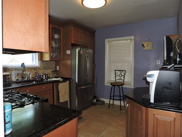 713 Colonial St, Uniondale, NY 11553 - kitchen featuring freestanding refrigerator, light tile patterned floors, glass insert cabinets, a sink, and tasteful backsplash