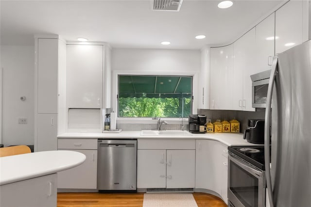 32 Overhill Rd, Yorktown Heights, NY 10598 - kitchen with stainless steel appliances, a sink, light countertops, white cabinetry, and light wood-style floors