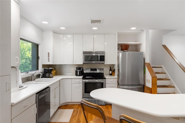 32 Overhill Rd, Yorktown Heights, NY 10598 - kitchen with appliances with stainless steel finishes, a sink, white cabinets, decorative backsplash, and light countertops