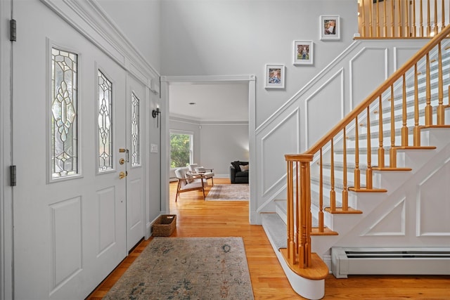 32 Woodcrest Ln, Goshen, NY 10924 - entrance foyer featuring baseboard heating, stairs, crown molding, and light wood-type flooring