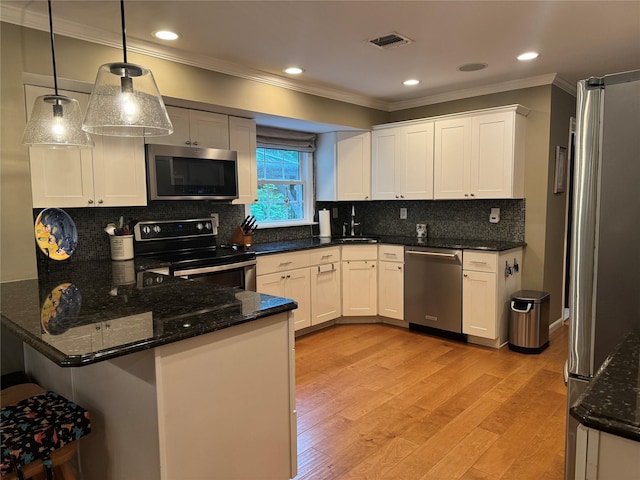 7 Yorkshire Ave, Stony Brook, NY 11790 - kitchen with appliances with stainless steel finishes, ornamental molding, a peninsula, dark stone counters, and decorative light fixtures