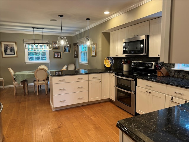 7 Yorkshire Ave, Stony Brook, NY 11790 - kitchen featuring appliances with stainless steel finishes, a peninsula, healthy amount of natural light, ornamental molding, and backsplash