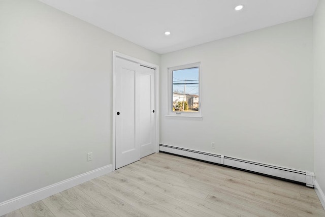2850 Shore Rd, Seaford, NY 11783 - unfurnished bedroom featuring baseboard heating, light wood-type flooring, baseboards, recessed lighting, and a closet
