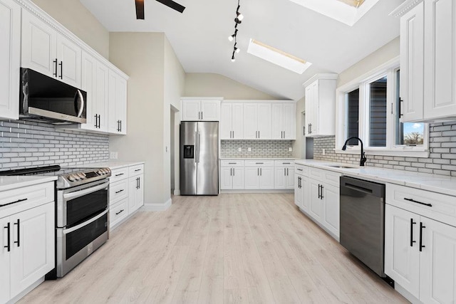 2850 Shore Rd, Seaford, NY 11783 - kitchen with stainless steel appliances, a sink, a skylight, backsplash, and white cabinetry