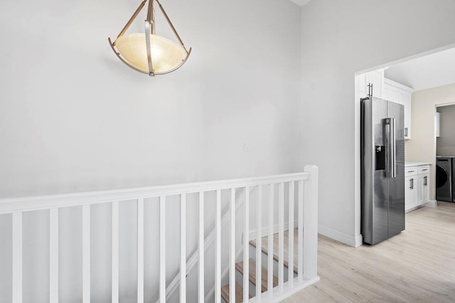2850 Shore Rd, Seaford, NY 11783 - hall with an upstairs landing, washer / clothes dryer, light wood-style floors, and baseboards