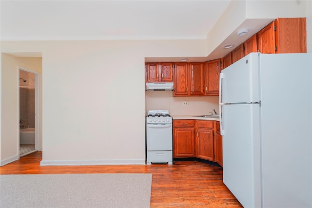 9430 Ridge Blvd Unit 6F, Brooklyn, NY 11209 - kitchen with white appliances, under cabinet range hood, wood finished floors, brown cabinetry, and light countertops