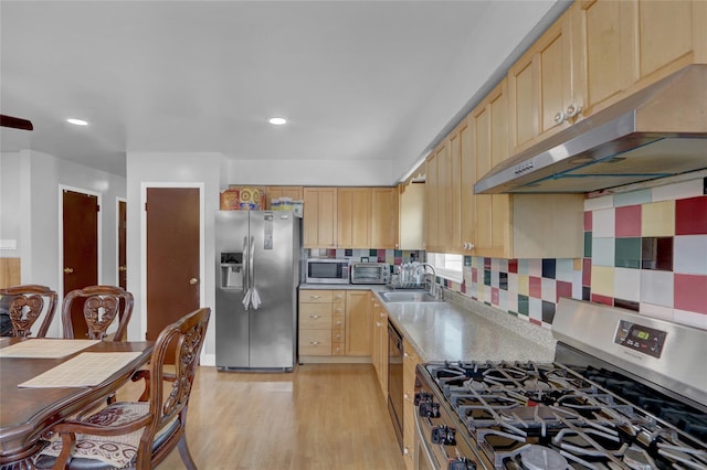 104 S 3rd St, New Hyde Park, NY 11040 - kitchen with appliances with stainless steel finishes, light brown cabinets, under cabinet range hood, light wood-type flooring, and decorative backsplash