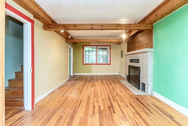 872-874 Rte 212, Saugerties, NY 12477 - unfurnished living room with beamed ceiling, a tile fireplace, light wood-type flooring, stairway, and baseboards