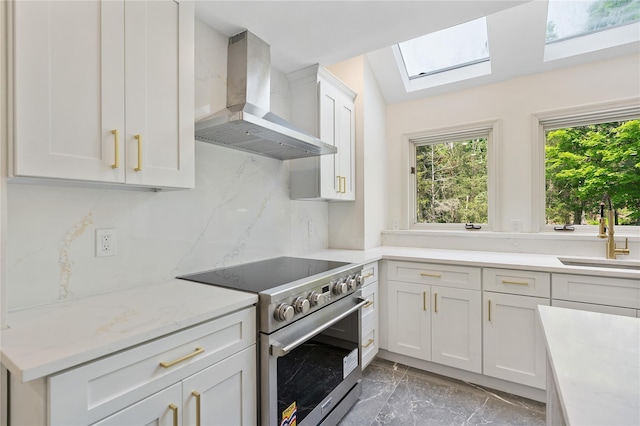 17 Royal Ct, Warwick, NY 10990 - kitchen with wall chimney exhaust hood, high end stainless steel range oven, light marble finish flooring, a skylight, and white cabinetry