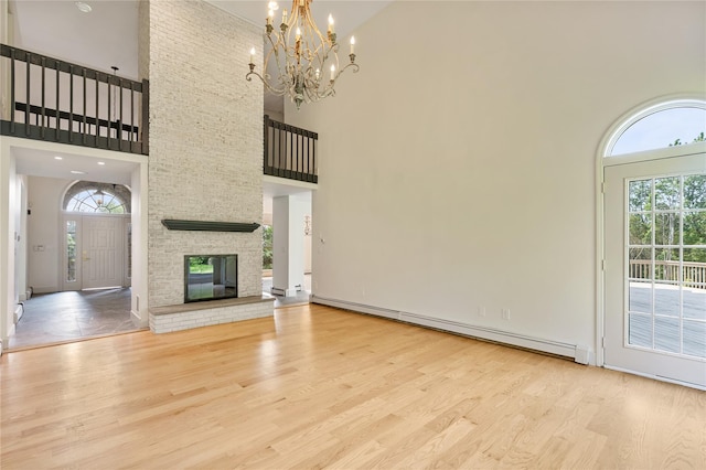 17 Royal Ct, Warwick, NY 10990 - unfurnished living room with a high ceiling, a baseboard heating unit, wood finished floors, a chandelier, and a large fireplace