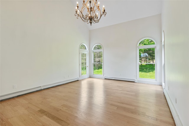 17 Royal Ct, Warwick, NY 10990 - empty room featuring a towering ceiling, a baseboard radiator, light wood-style flooring, a chandelier, and plenty of natural light