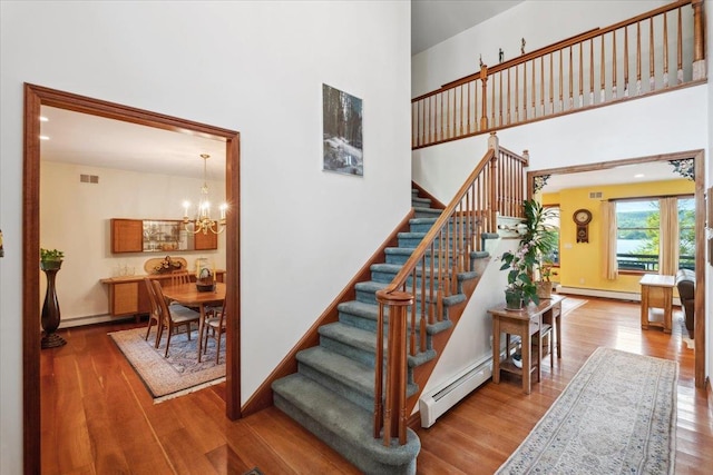 1034 Rte 292, Holmes, NY 12531 - staircase with baseboard heating, wood finished floors, a baseboard radiator, a chandelier, and a towering ceiling