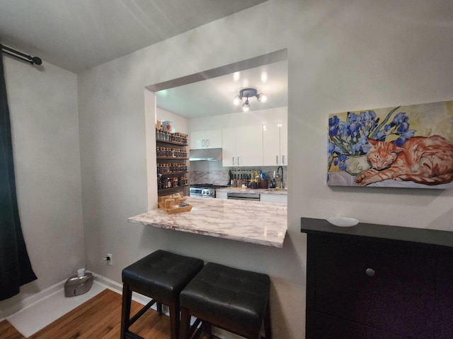 64-15 Springfield Blvd Unit A, Oakland Gardens, NY 11364 - kitchen with under cabinet range hood, stainless steel gas range oven, wood finished floors, white cabinets, and a breakfast bar area