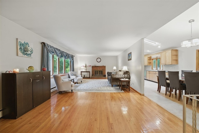 99 Furnace Dock Rd, Croton-On-Hudson, NY 10520 - living area featuring light wood-type flooring, a baseboard radiator, and a brick fireplace