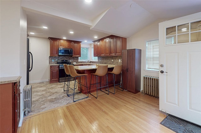 33 Hollowbrook Ct N, Cortlandt Manor, NY 10567 - kitchen with stainless steel appliances, radiator heating unit, light wood-style flooring, decorative backsplash, and recessed lighting