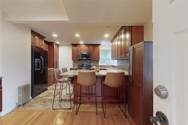 33 Hollowbrook Ct N, Cortlandt Manor, NY 10567 - kitchen with appliances with stainless steel finishes, radiator, a peninsula, light wood-style flooring, and tasteful backsplash