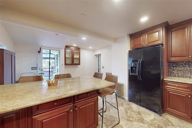 33 Hollowbrook Ct N, Cortlandt Manor, NY 10567 - kitchen featuring black fridge with ice dispenser, a breakfast bar area, decorative backsplash, glass insert cabinets, and light stone counters
