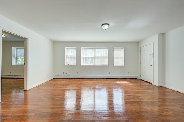 39-32 54th St, Woodside, NY 11377 - spare room featuring baseboard heating, plenty of natural light, wood finished floors, and baseboards
