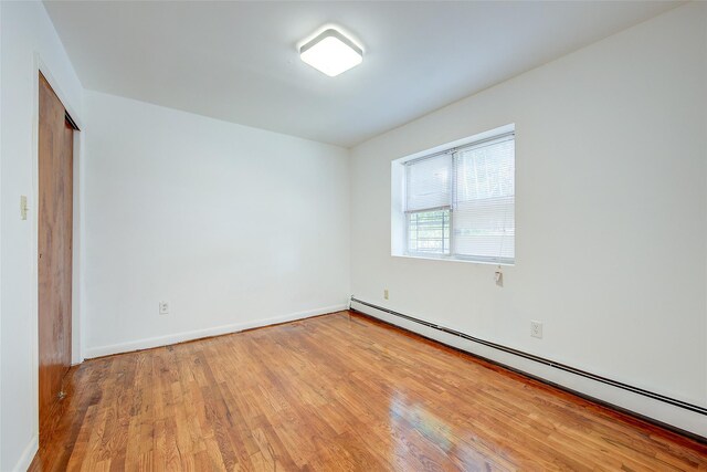 39-32 54th St, Woodside, NY 11377 - unfurnished room featuring a baseboard heating unit, light wood-style flooring, and baseboards