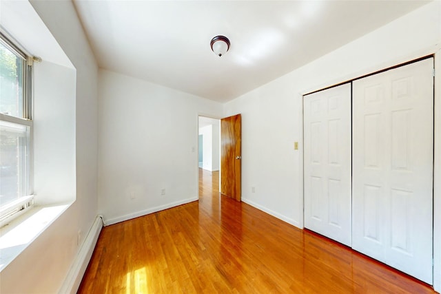 39-32 54th St, Woodside, NY 11377 - unfurnished bedroom featuring wood finished floors, baseboards, baseboard heating, and a closet
