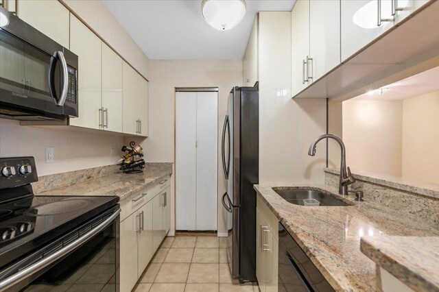 615 Broadway Unit 85, Amityville, NY 11701 - kitchen featuring black electric range oven, freestanding refrigerator, dishwashing machine, white cabinets, and light stone countertops