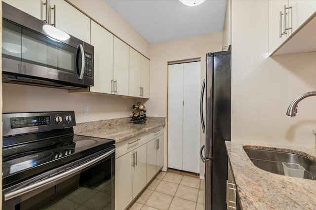 615 Broadway Unit 85, Amityville, NY 11701 - kitchen with electric range oven, freestanding refrigerator, white cabinetry, light stone countertops, and light tile patterned floors