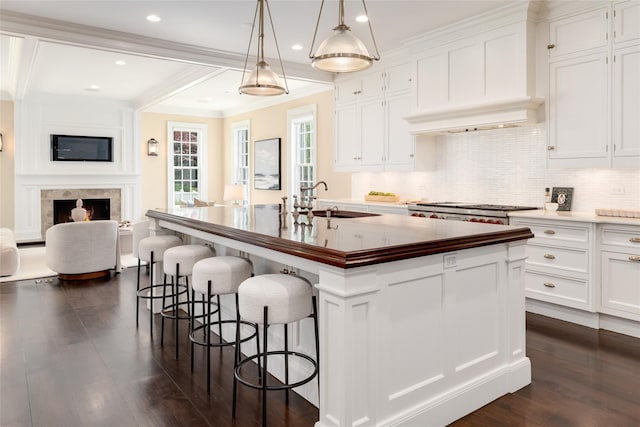 21 Dorann Rd, Purchase, NY 10577 - kitchen featuring dark wood finished floors, decorative backsplash, a center island with sink, white cabinetry, and crown molding